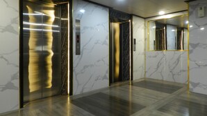Un ascensor con pantalla digital, paredes de mármol y suelo pulido.