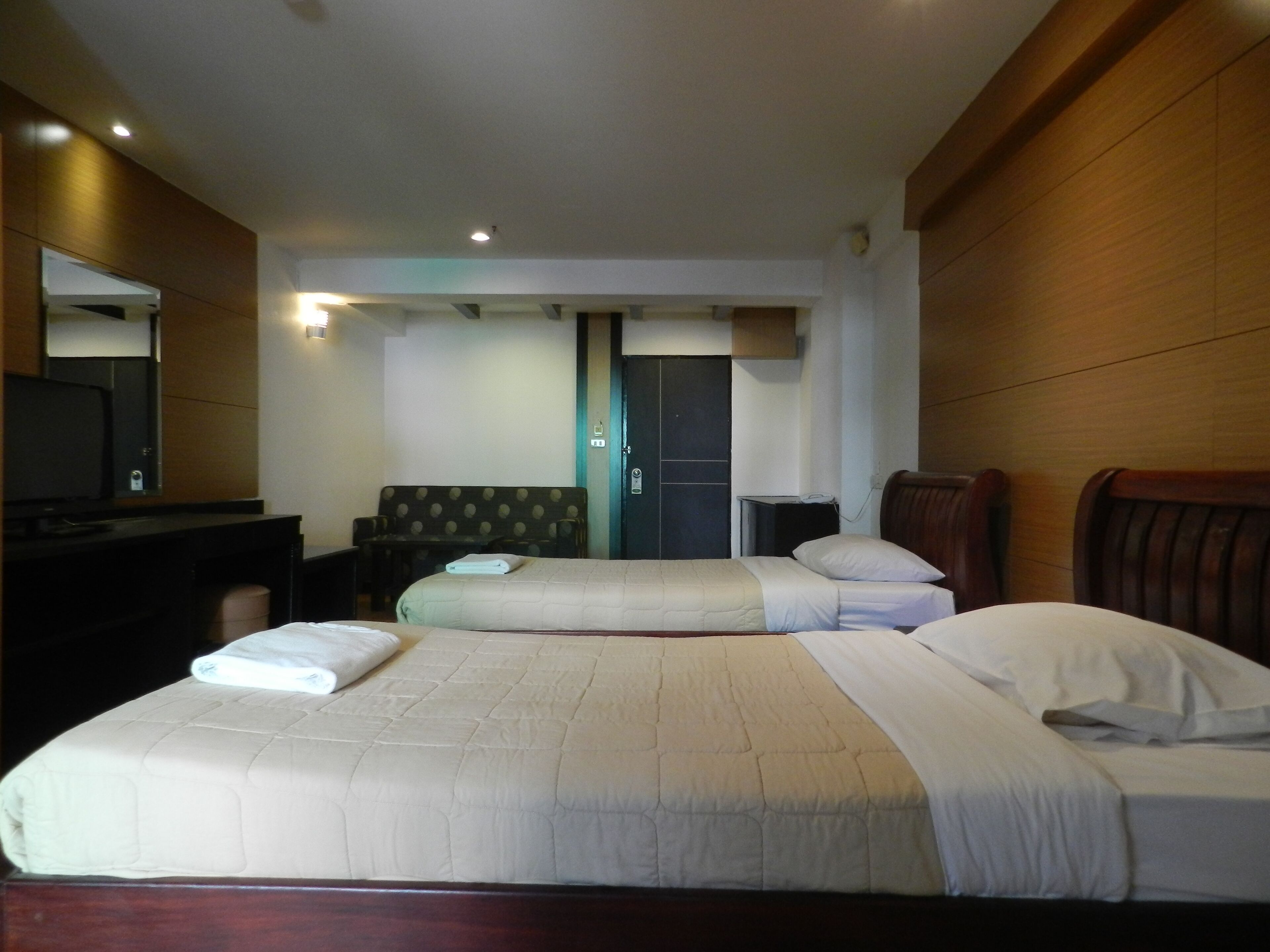A hotel room with two beds, a desk, a television, and a door.