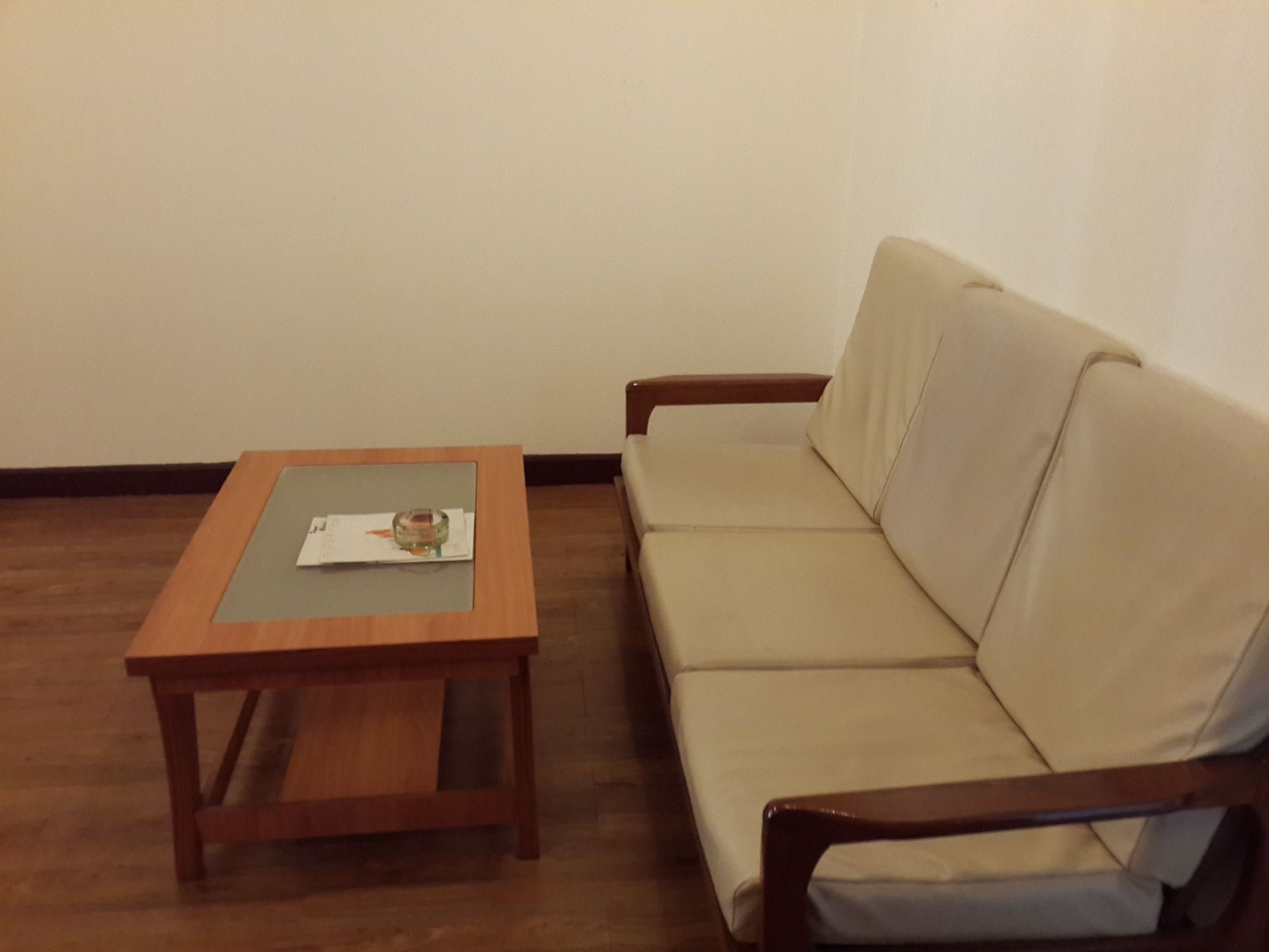 Een kamer met een houten salontafel en een beige bank.