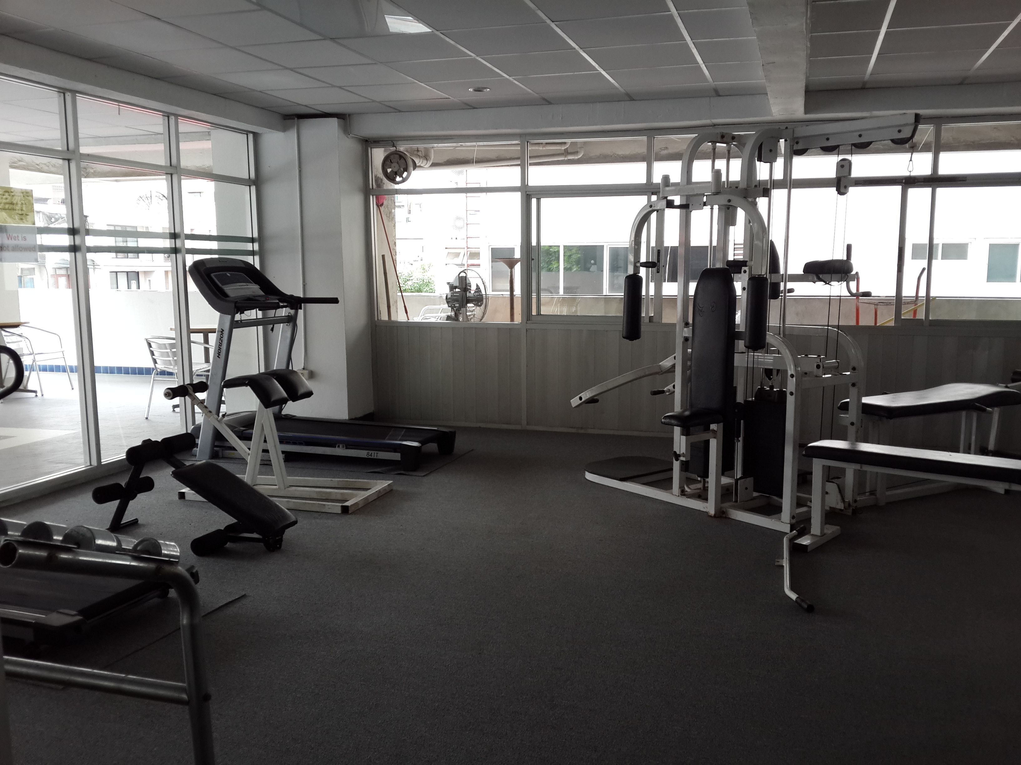A gym with cardio equipment, weight machines, and benches.