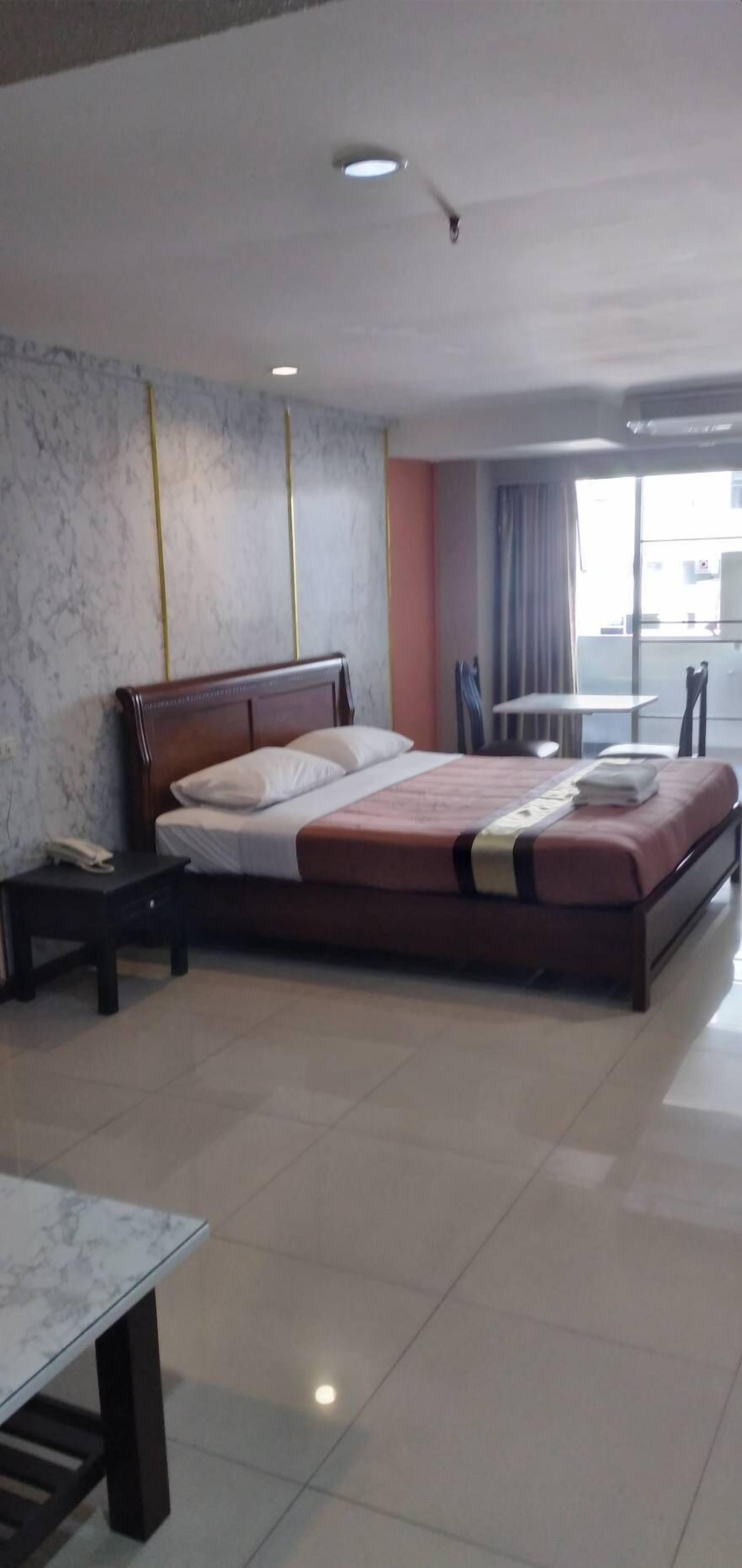 Habitación de hotel con una cama grande, una mesita pequeña y una silla.