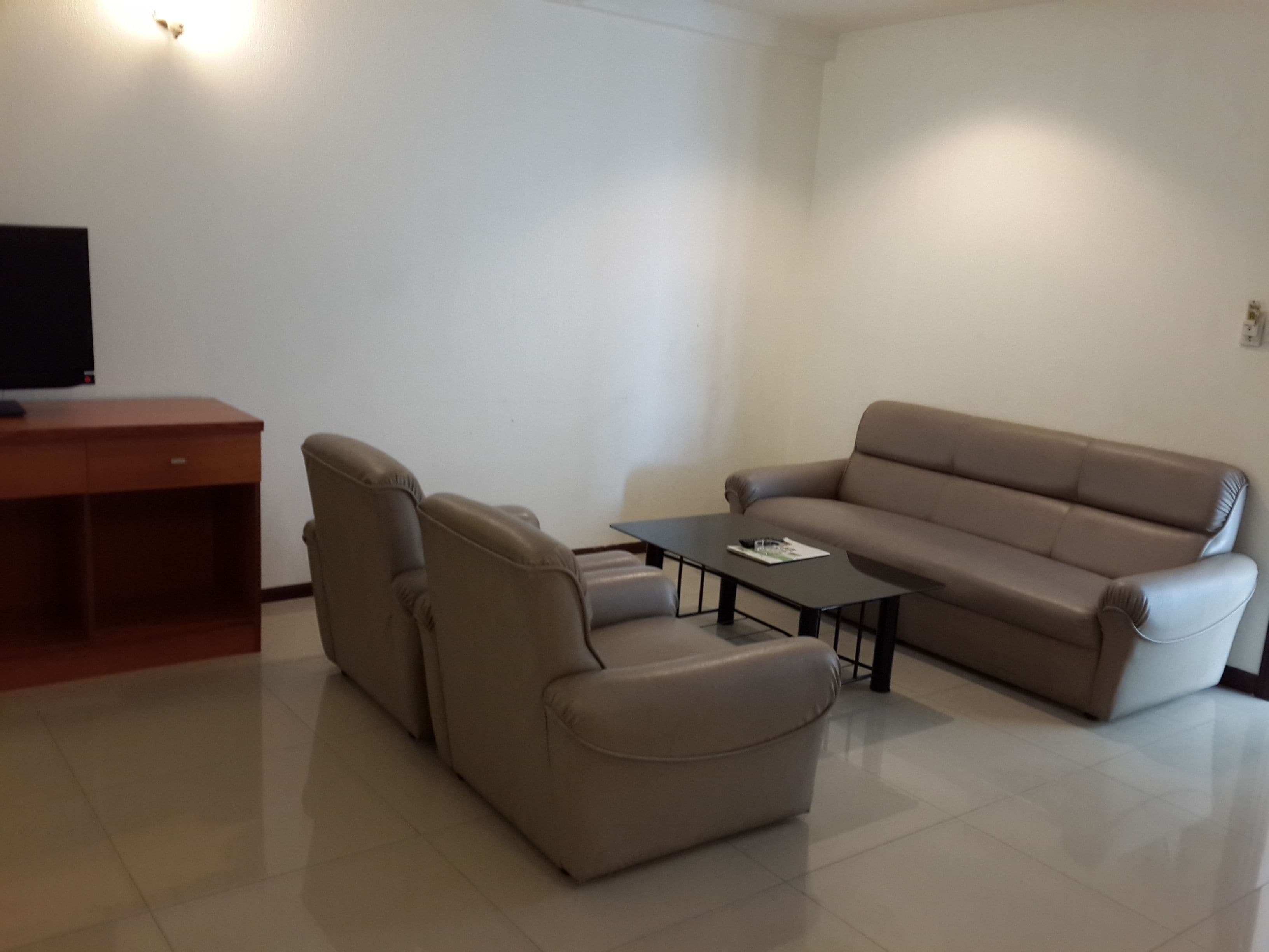 A living room with a sofa, a recliner, a coffee table, and a TV on a stand.