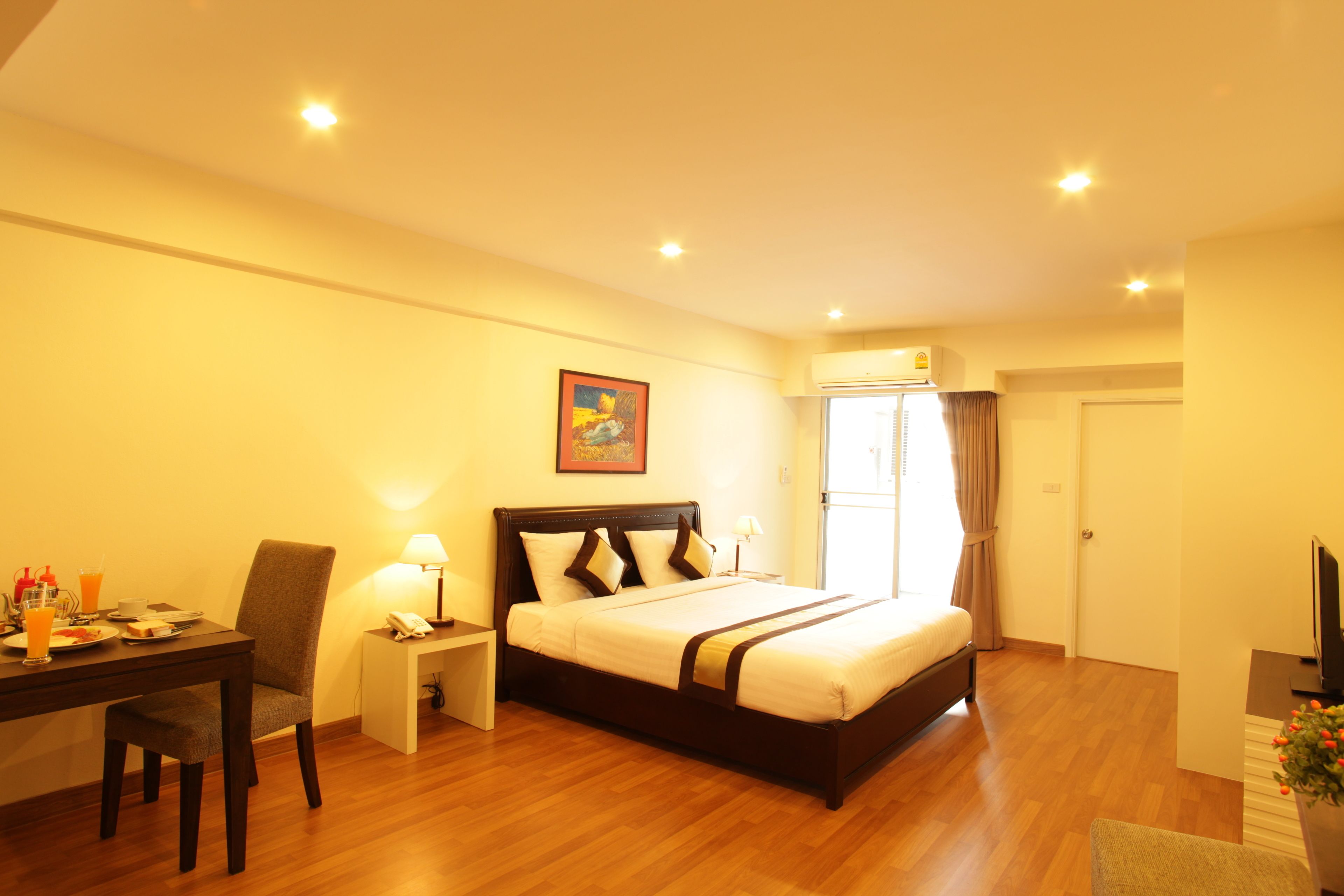 A hotel room with a bed, a desk, a chair, a lamp, and a television.