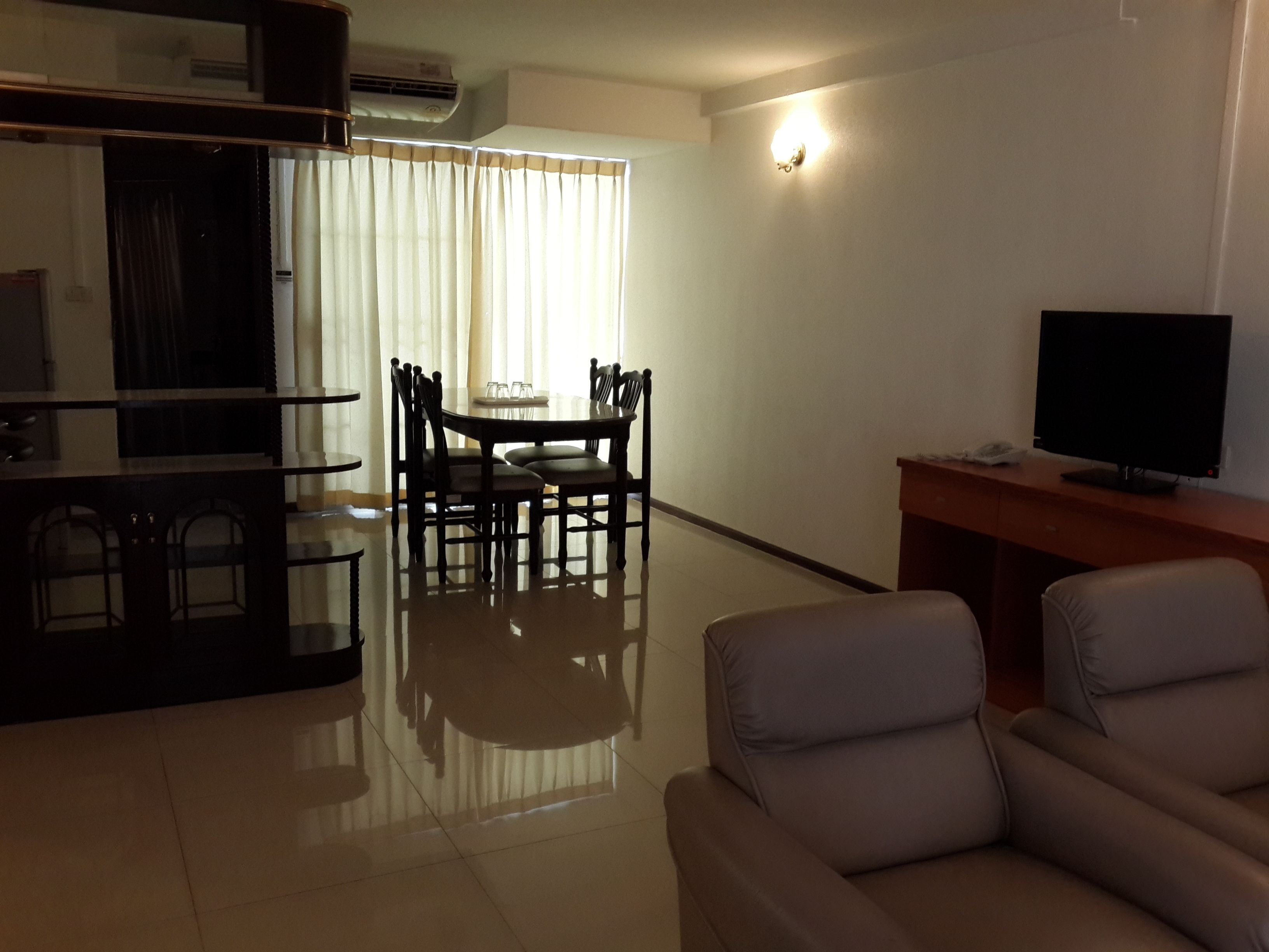 Una sala de estar moderna con televisor de pantalla plana, un comedor con mesa y sillas, y un sofá.