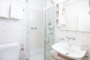 A bathroom with a glass-enclosed shower, a white sink, and a toilet. - Hotel Polo Inn (Ascona)