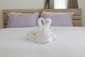 A neatly made bed with a towel arranged in the shape of two swans.