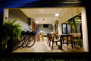 A dining area with wooden furniture, bicycles, and potted plants.