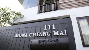 Un bâtiment sur lequel on peut lire l’inscription « 111 MONA CHIANG MAI » et qui est agrémenté d’un élément décoratif en dessous.