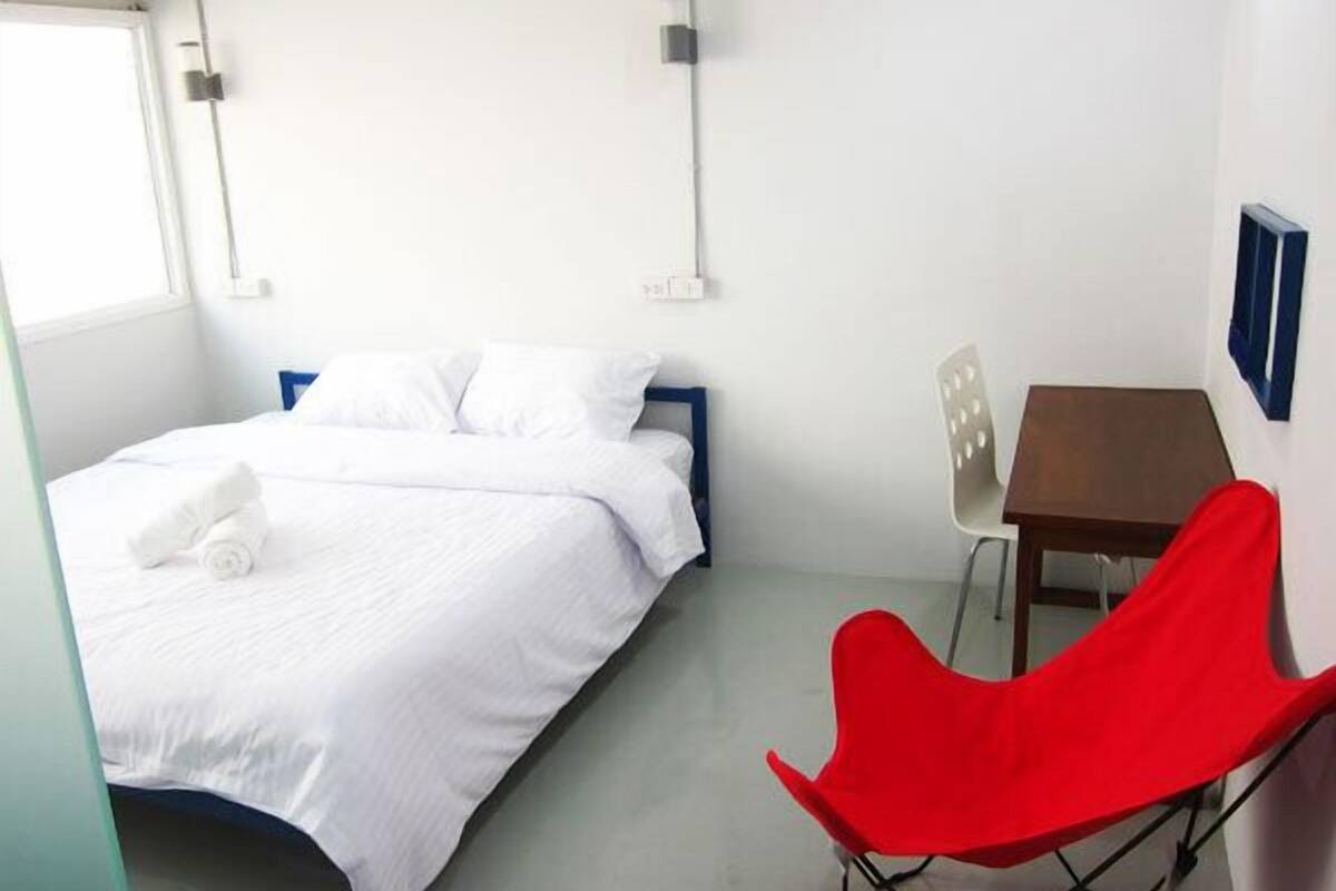 Een hotelkamer met een bed, een bureau en een rode stoel.