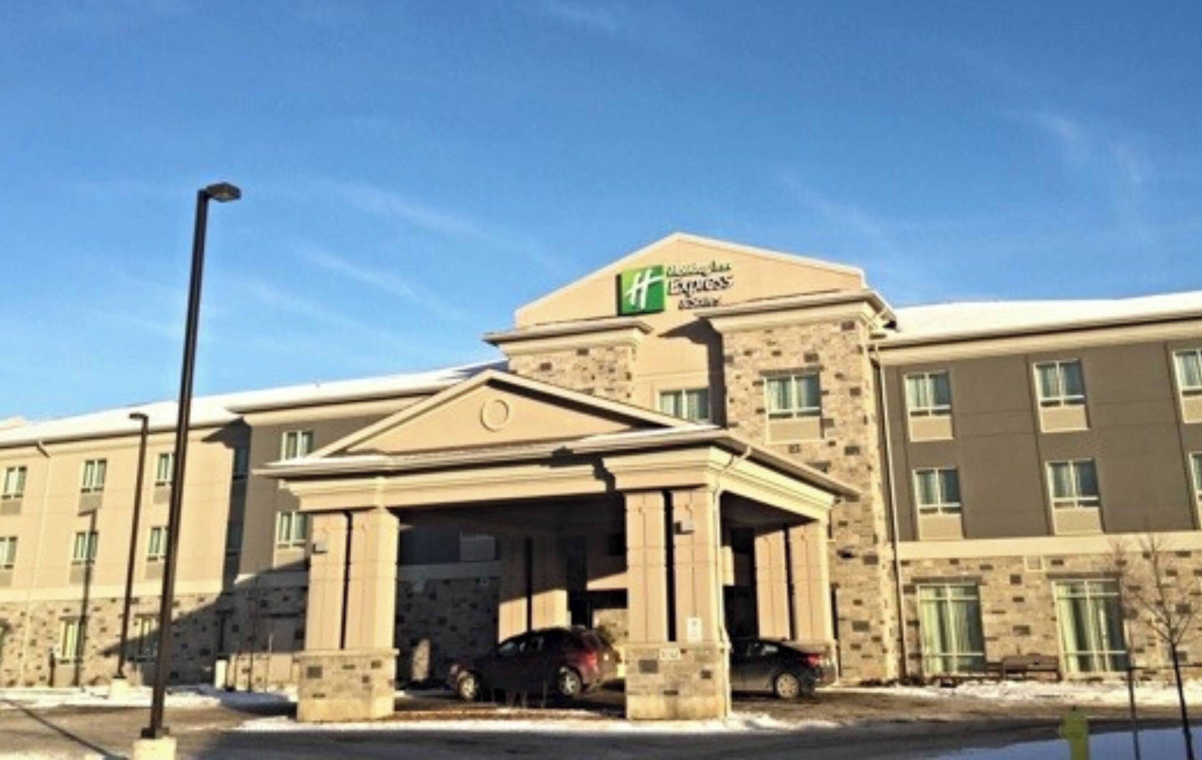 A hotel with a central entrance, multiple windows, and a clear sky.