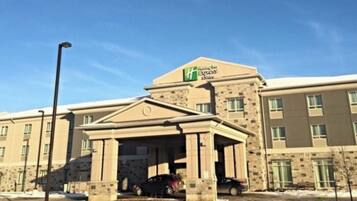 A hotel with a central entrance, multiple windows, and a clear sky.