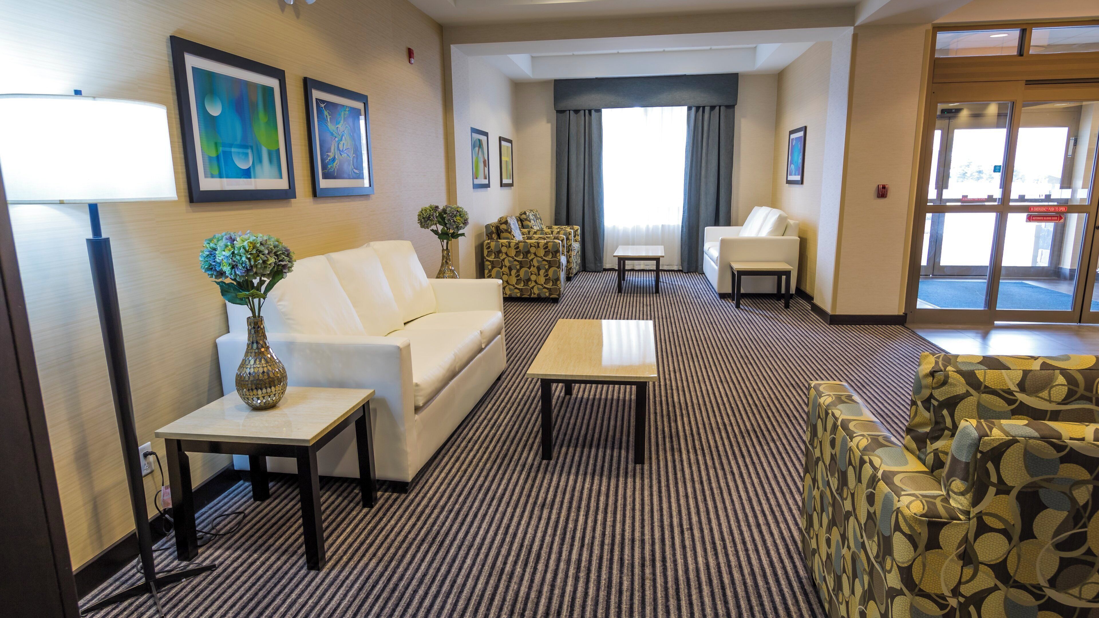 A hotel lobby with a sofa, armchair, and a small table with a vase of flowers.