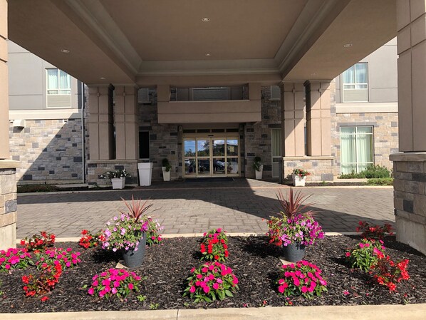 A hotel entrance with a covered walkway, stone facade, and potted plants. - Holiday Inn Express & Suites Thunder Bay by IHG (Thunder Bay)