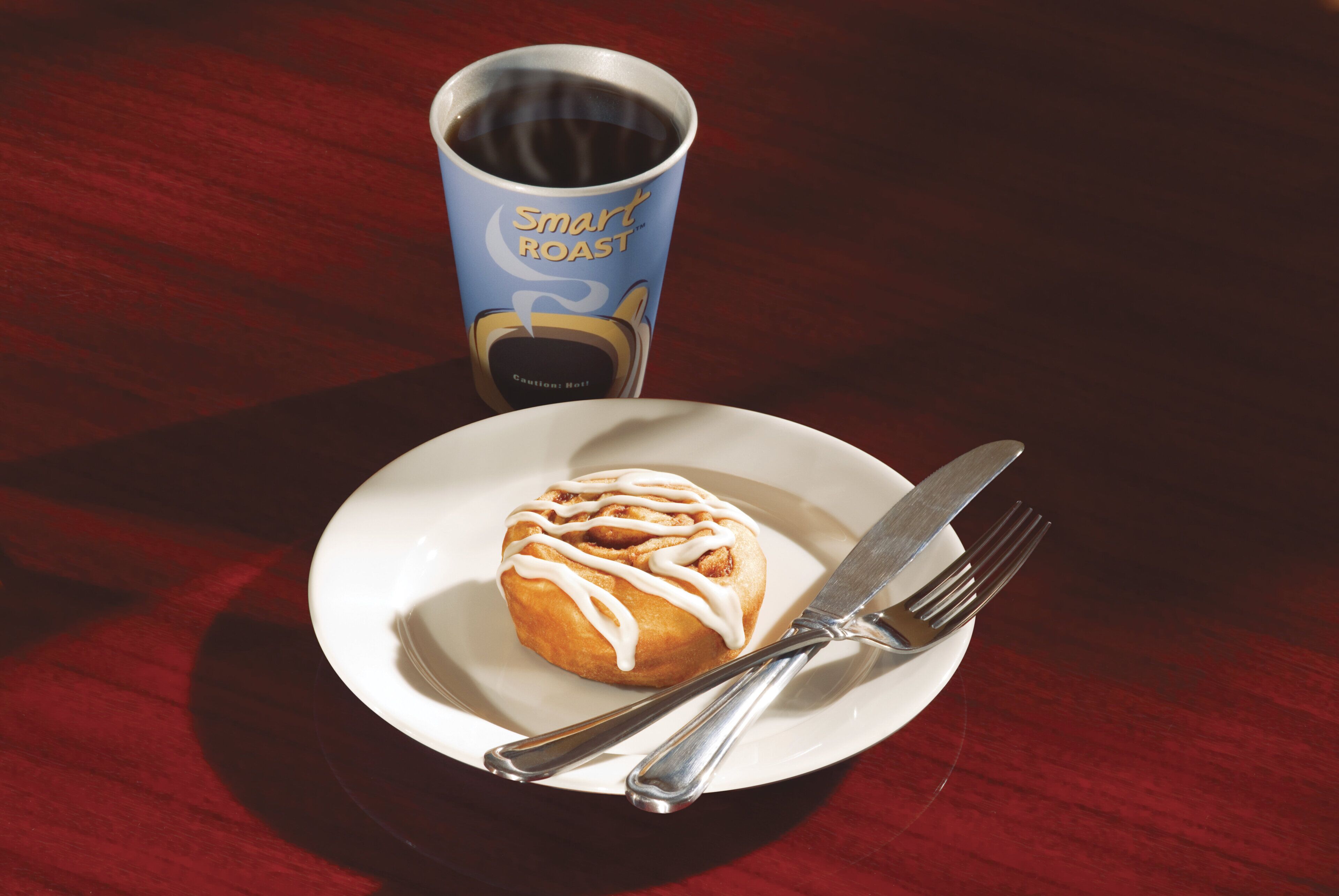Un plato con un pastel y una taza de café sobre una mesa de madera.