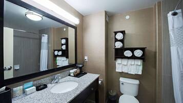 A modern bathroom with a granite sink, a large mirror, a toilet, and a shower curtain.