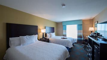 A hotel room with two beds, a desk, a chair, and a dresser.