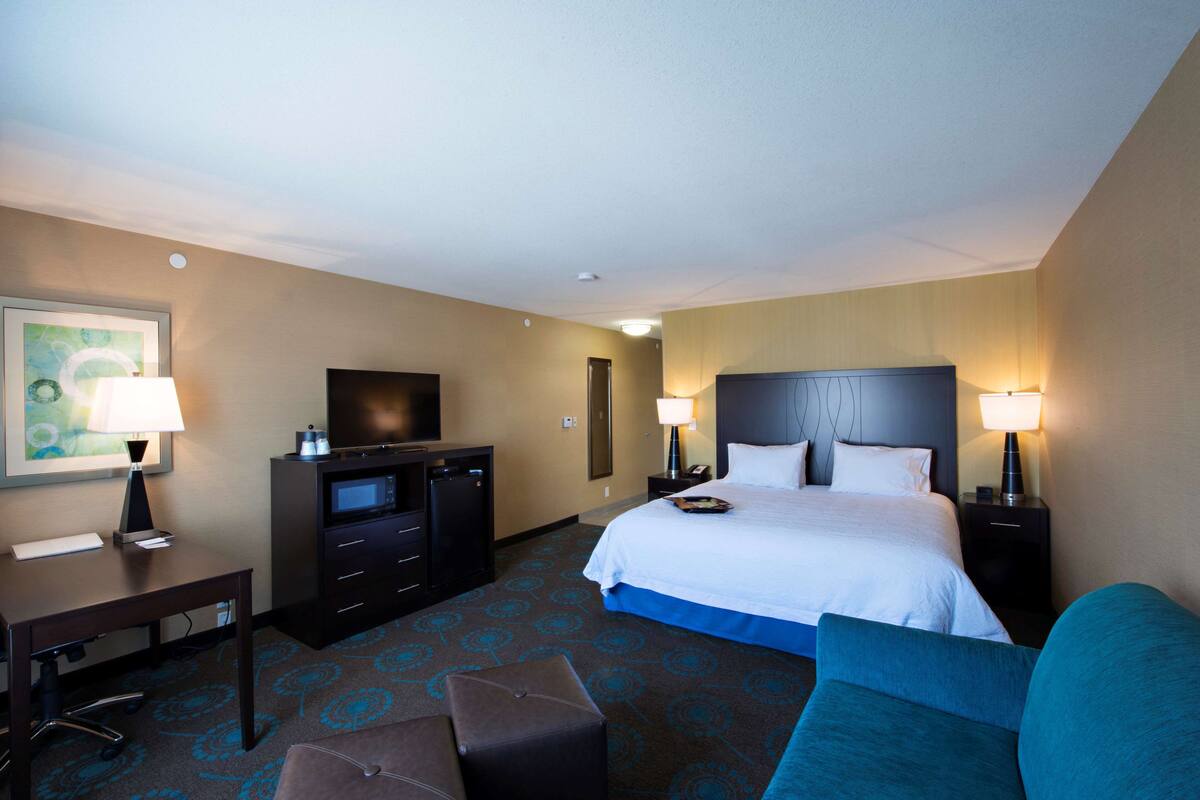 Habitación de hotel con cama, escritorio, televisor y zona de estar.