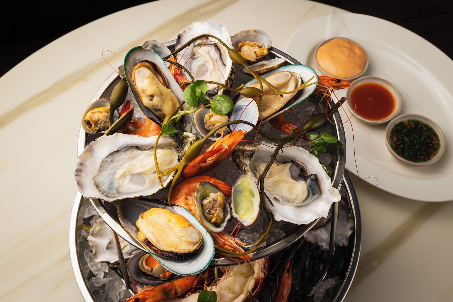 A seafood platter with various shellfish and a small plate of condiments.