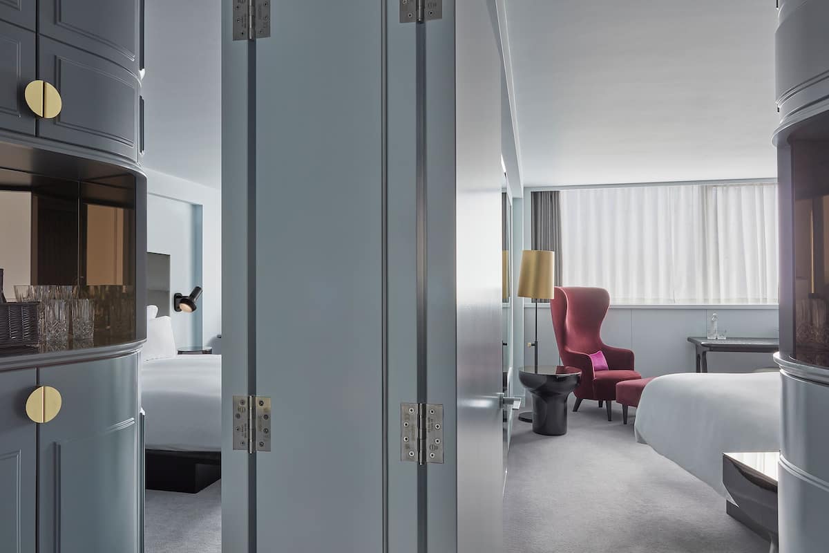 A hotel room with a bed, a desk, a chair, and a wardrobe.