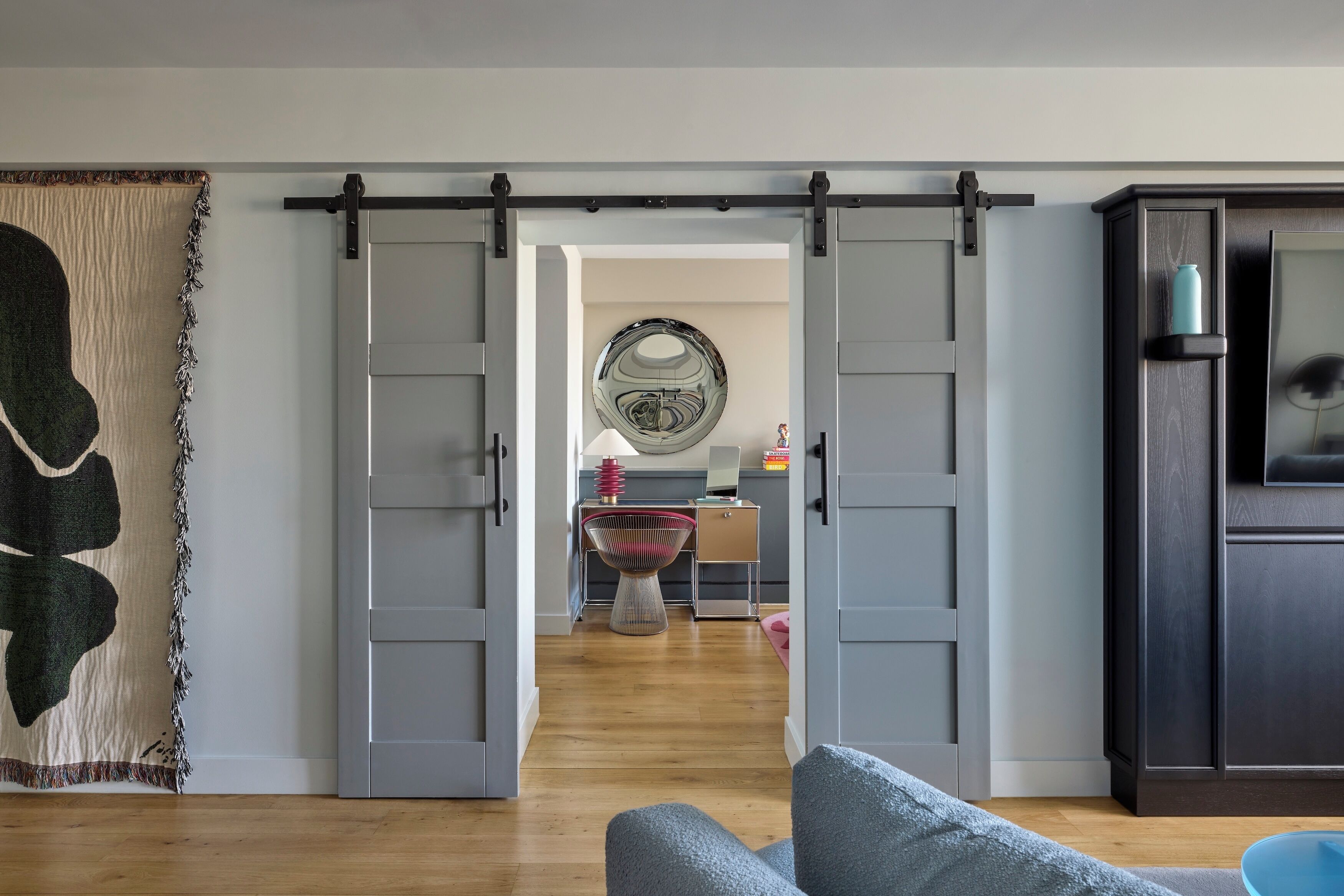 Quarto com porta deslizante para uma cozinha, um espelho grande e um armário azul.