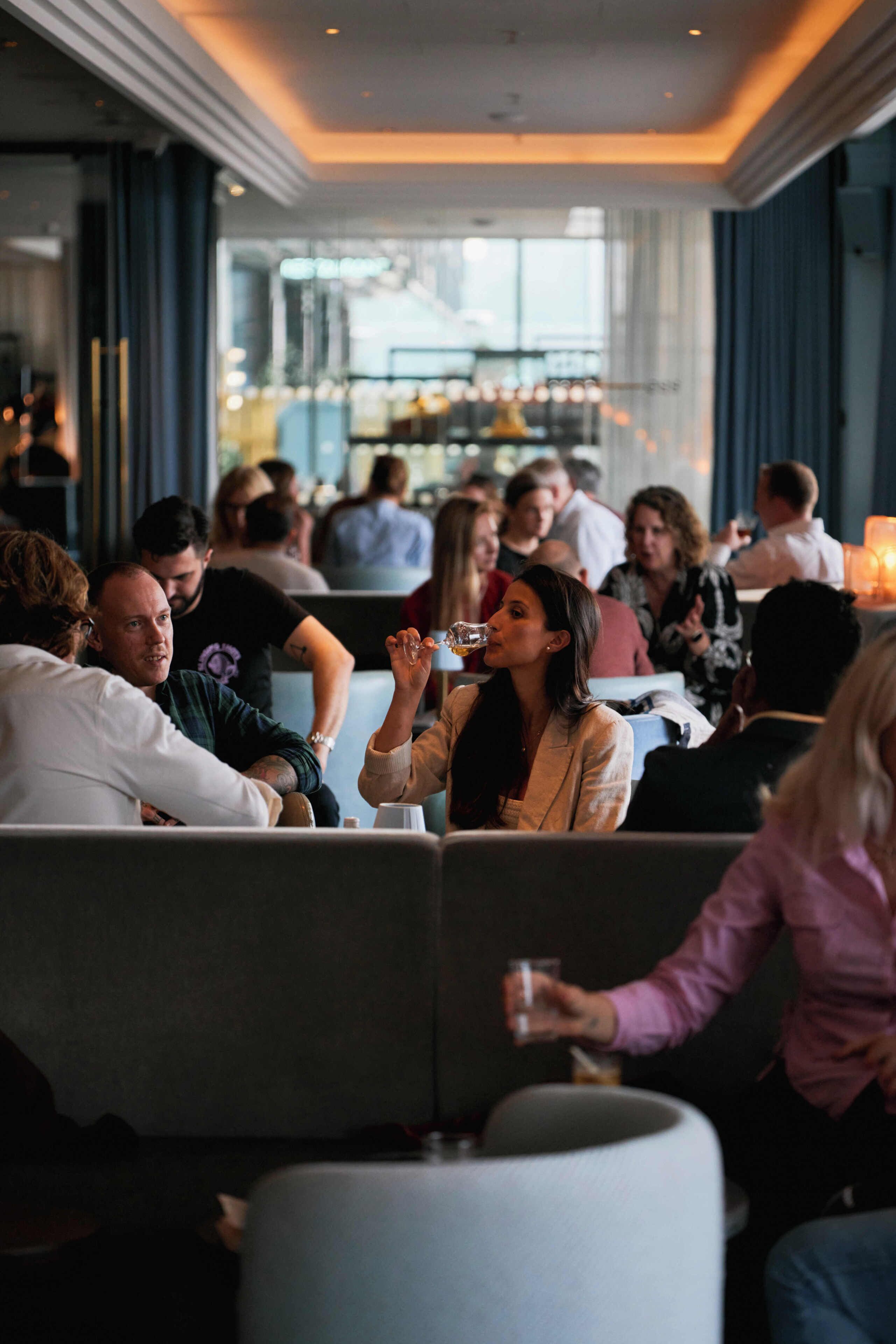 Un gruppo di persone sedute in un ambiente moderno con un'area bar sullo sfondo.