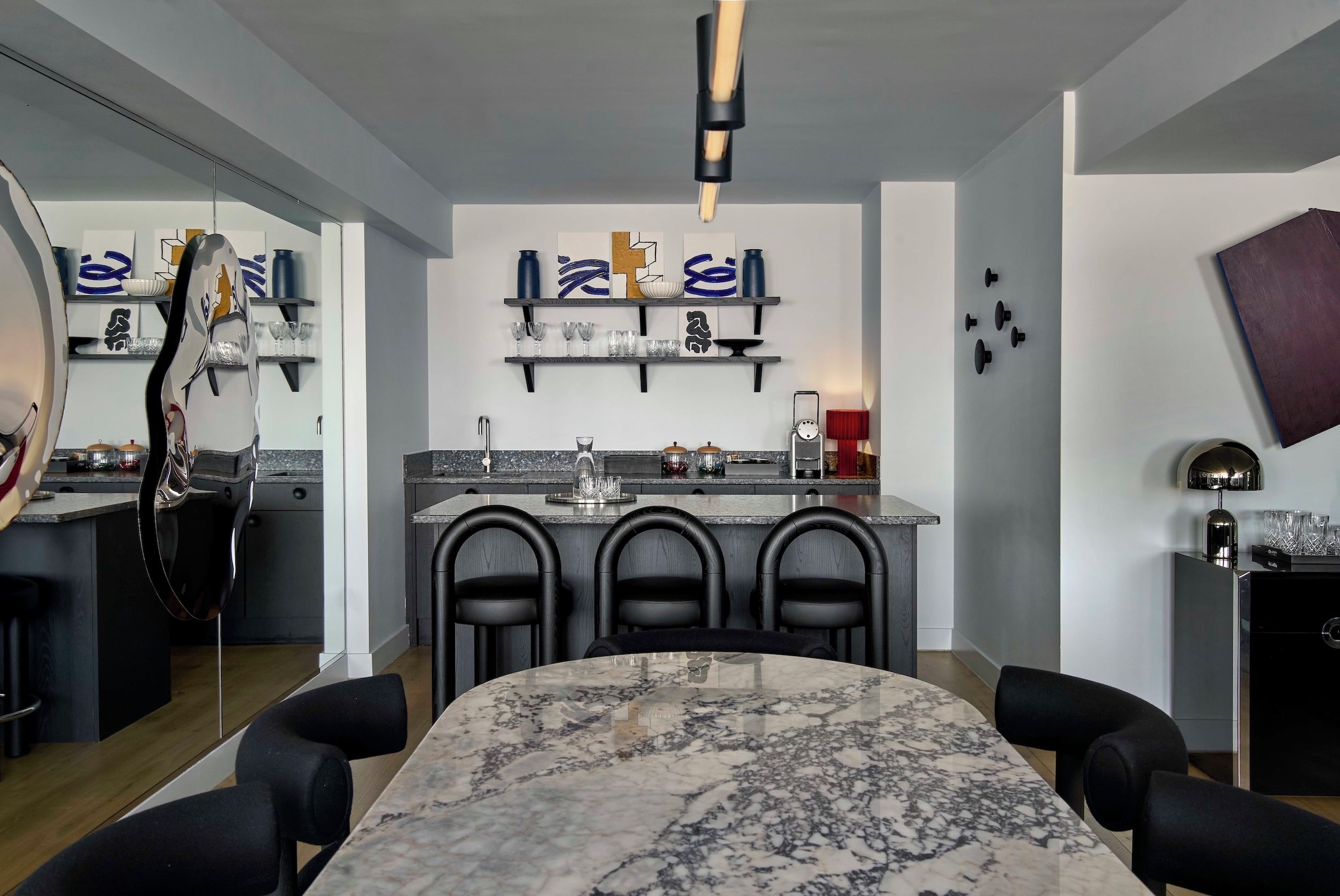 A modern kitchen with a marble island, black chairs, and a dining table.