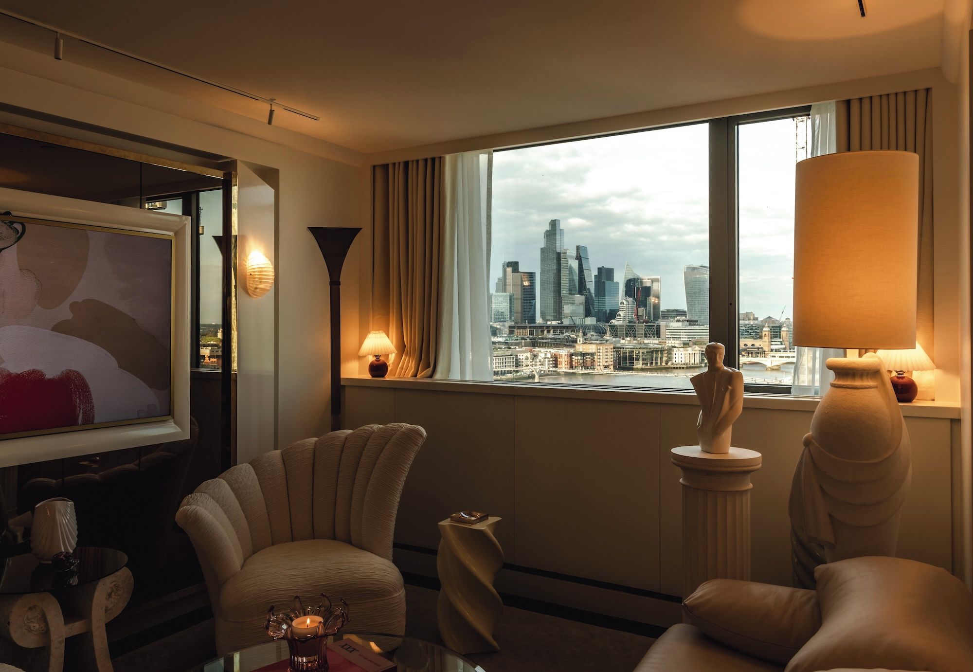 Une chambre d’hôtel avec vue sur la ville, un canapé, une lampe et un vase décoratif.