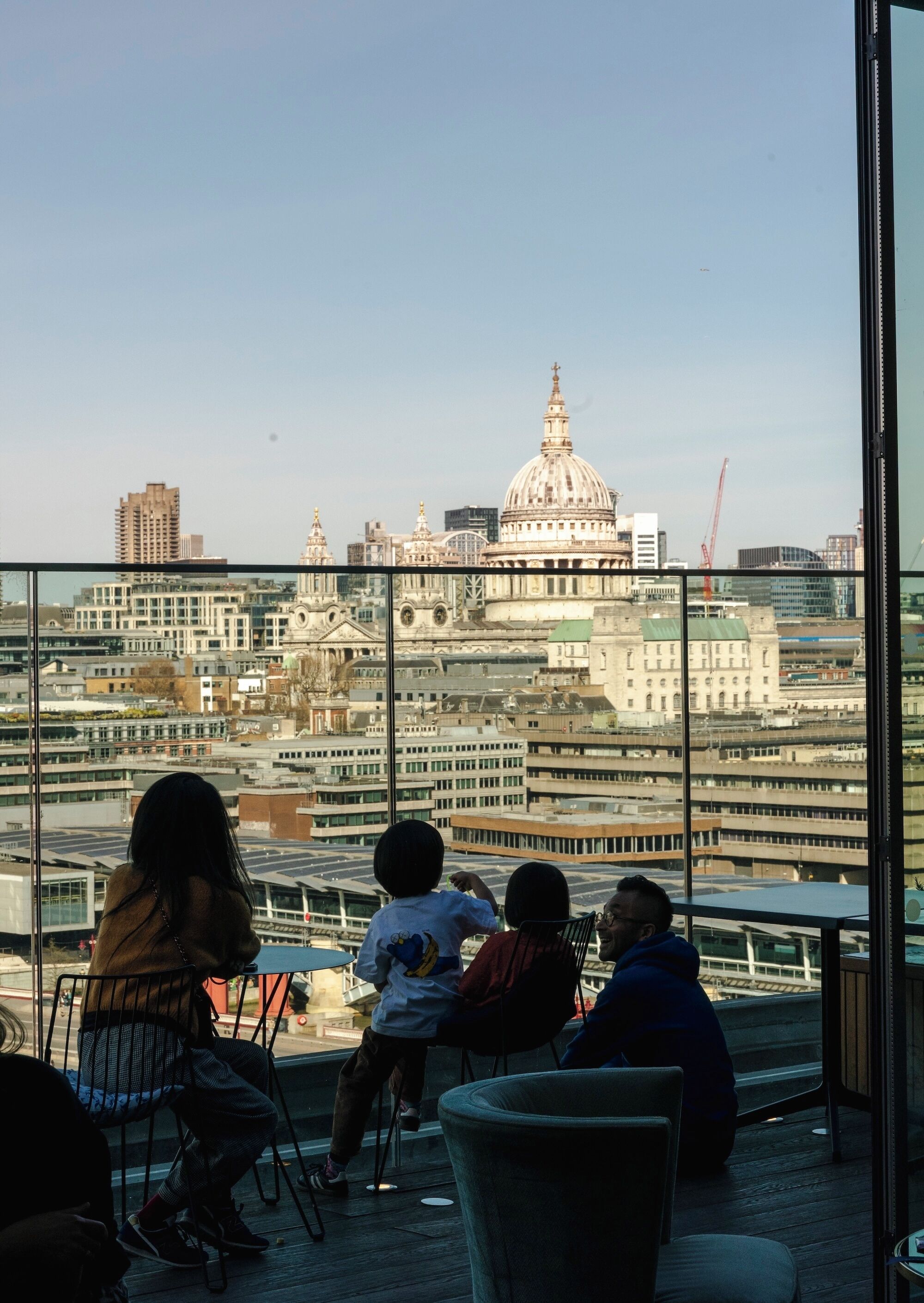 Vista da un grattacielo con un'ampia vetrata, che si affaccia su un paesaggio urbano con diversi edifici, tra cui una cupola imponente.
