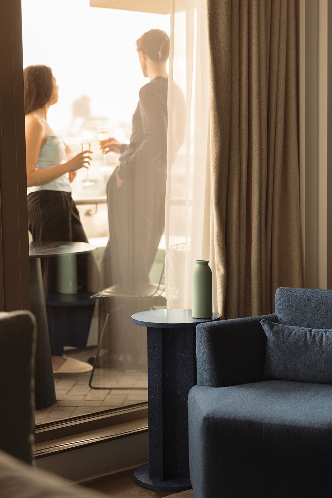 Una habitación de hotel con vista a la ciudad, una mesa redonda y un sillón azul.
