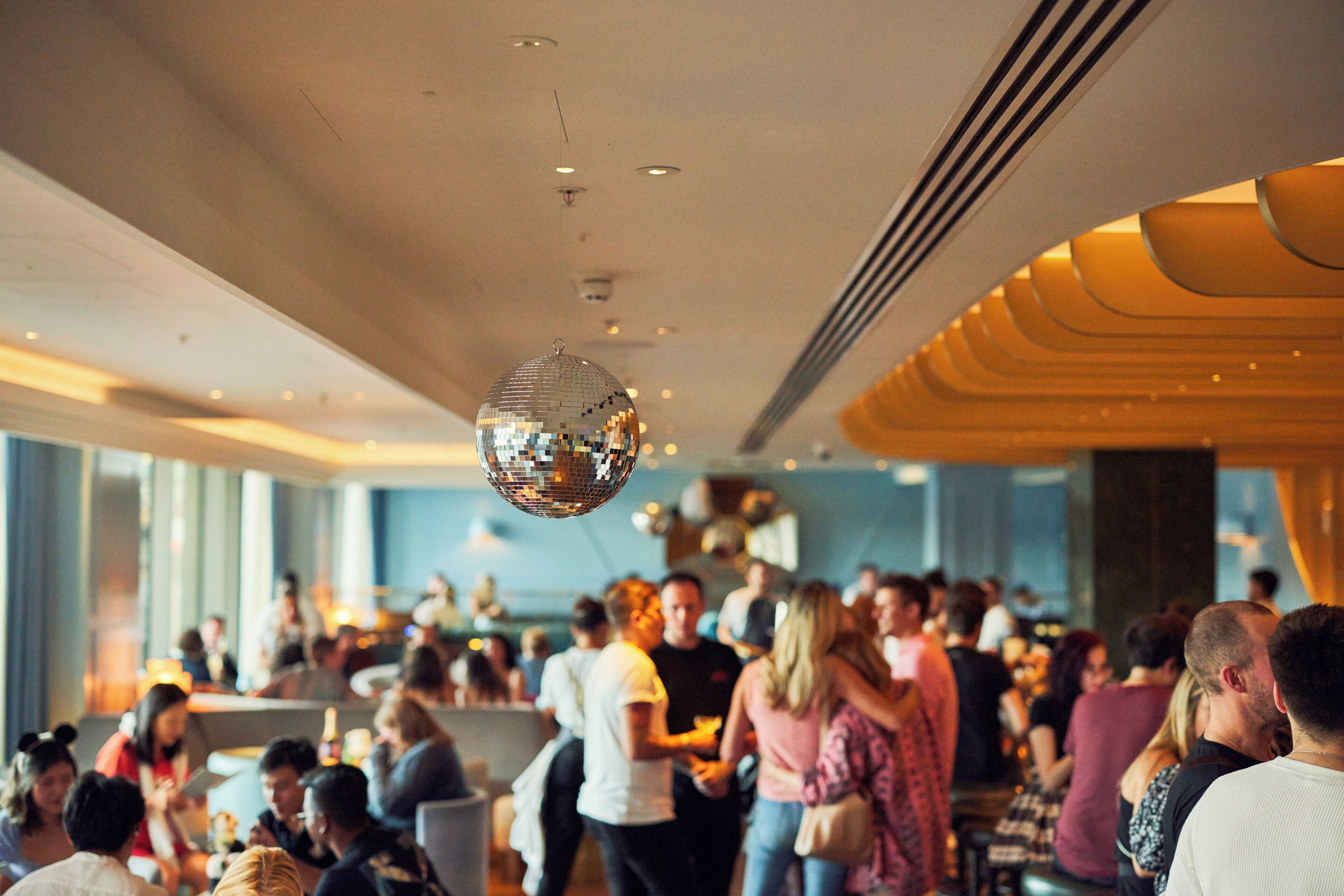 A crowded indoor space with a disco ball hanging from the ceiling.