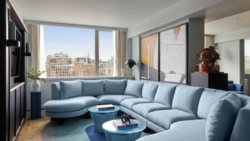 Een moderne woonkamer met een grote L-vormige hoekbank, twee ronde salontafels en een stadszicht door grote ramen.
