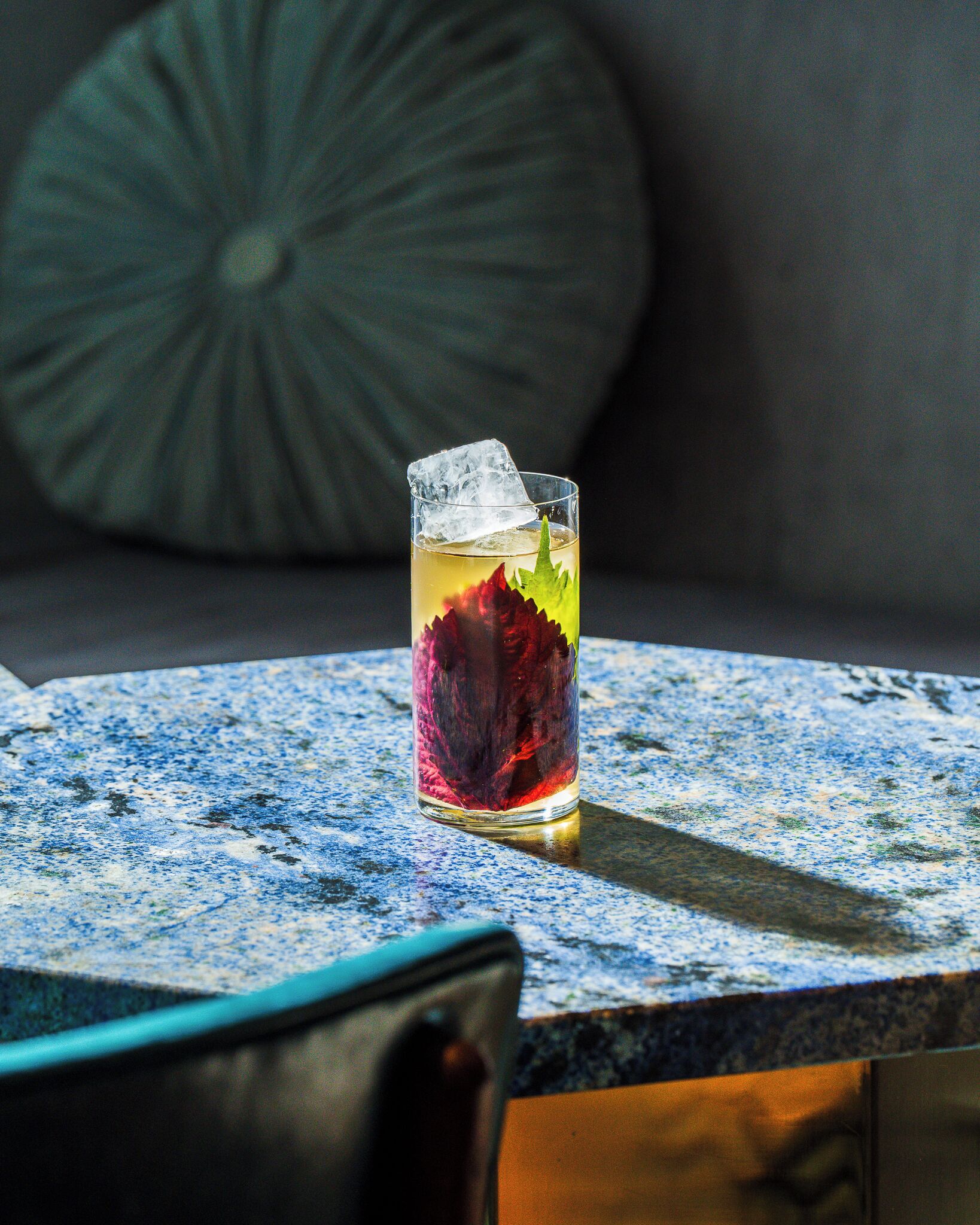 A glass with a beverage and ice on a table.