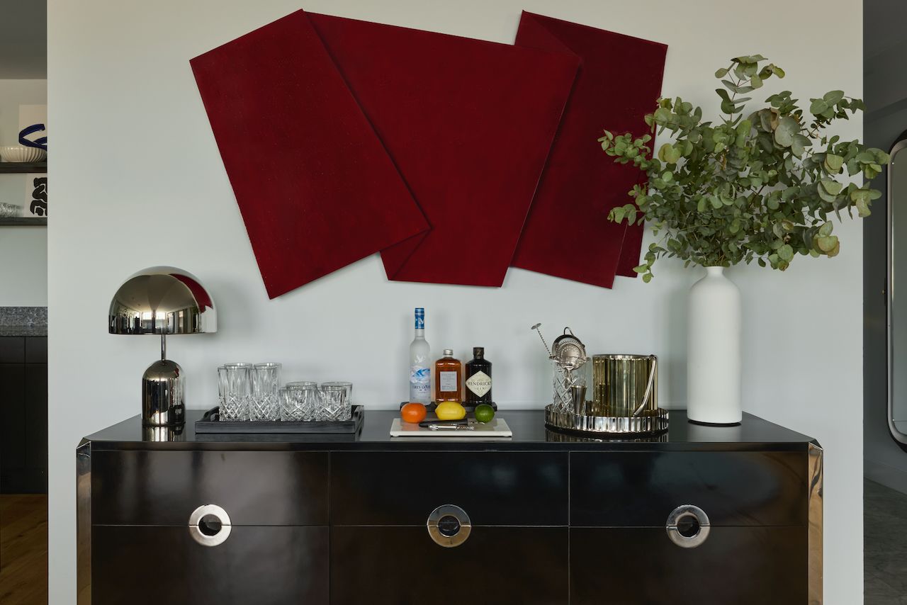 A bar area with a counter, glasses, bottles, and a decorative plant.