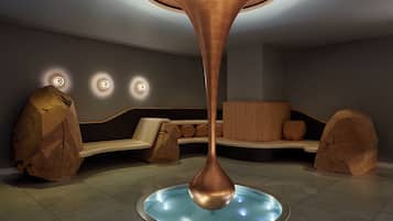 A modern interior with a central copper sculpture, a seating area with wooden accents, and recessed lighting.