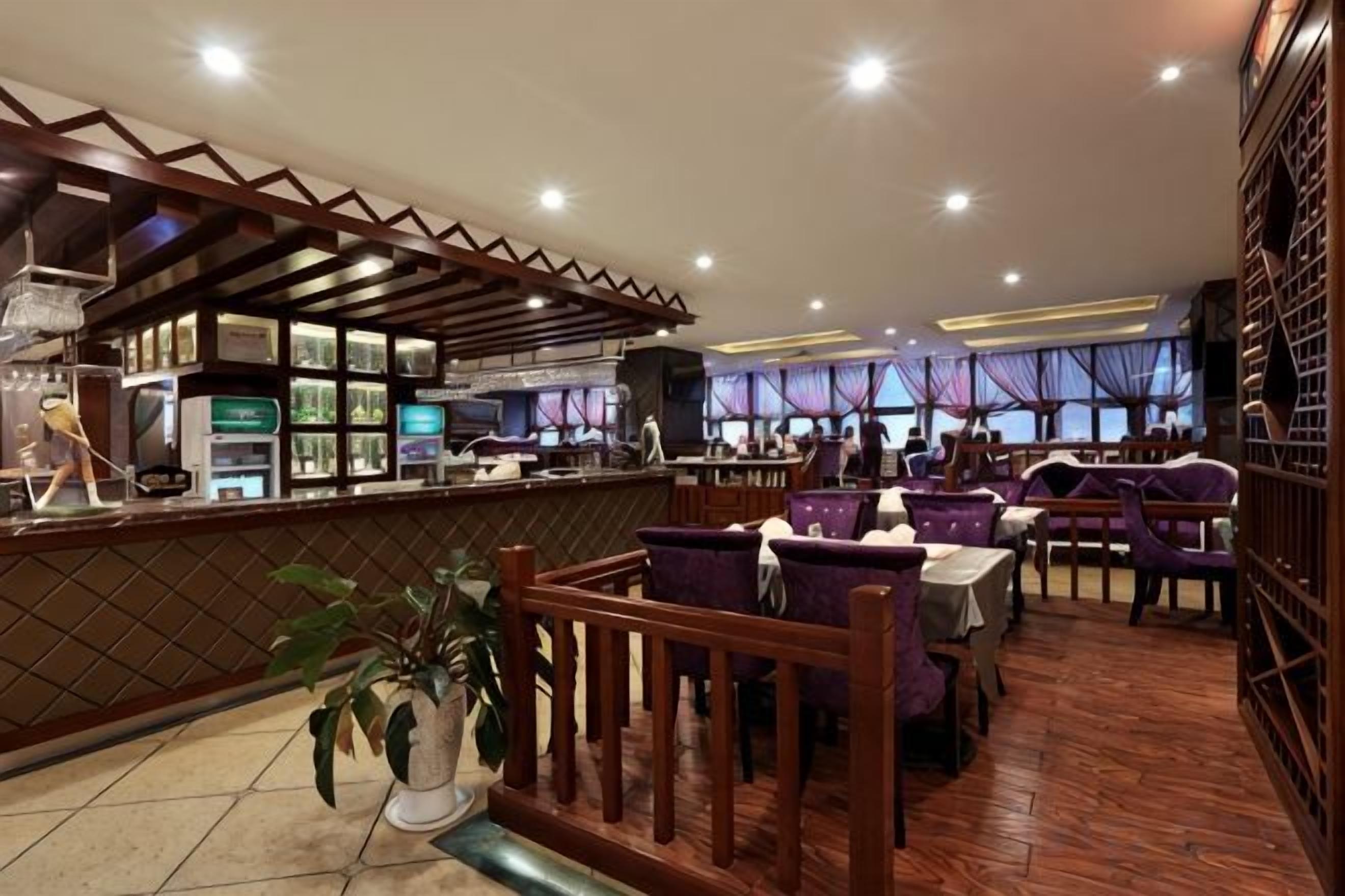 A restaurant with a bar area, seating with purple chairs, and a tiled floor.