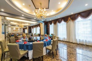 A conference room with round tables, chairs, and a chandelier.