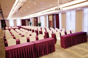A conference room with rows of white chairs and tables, large windows, and a carpeted floor. - Shenhang International Hotel (Zunyi)