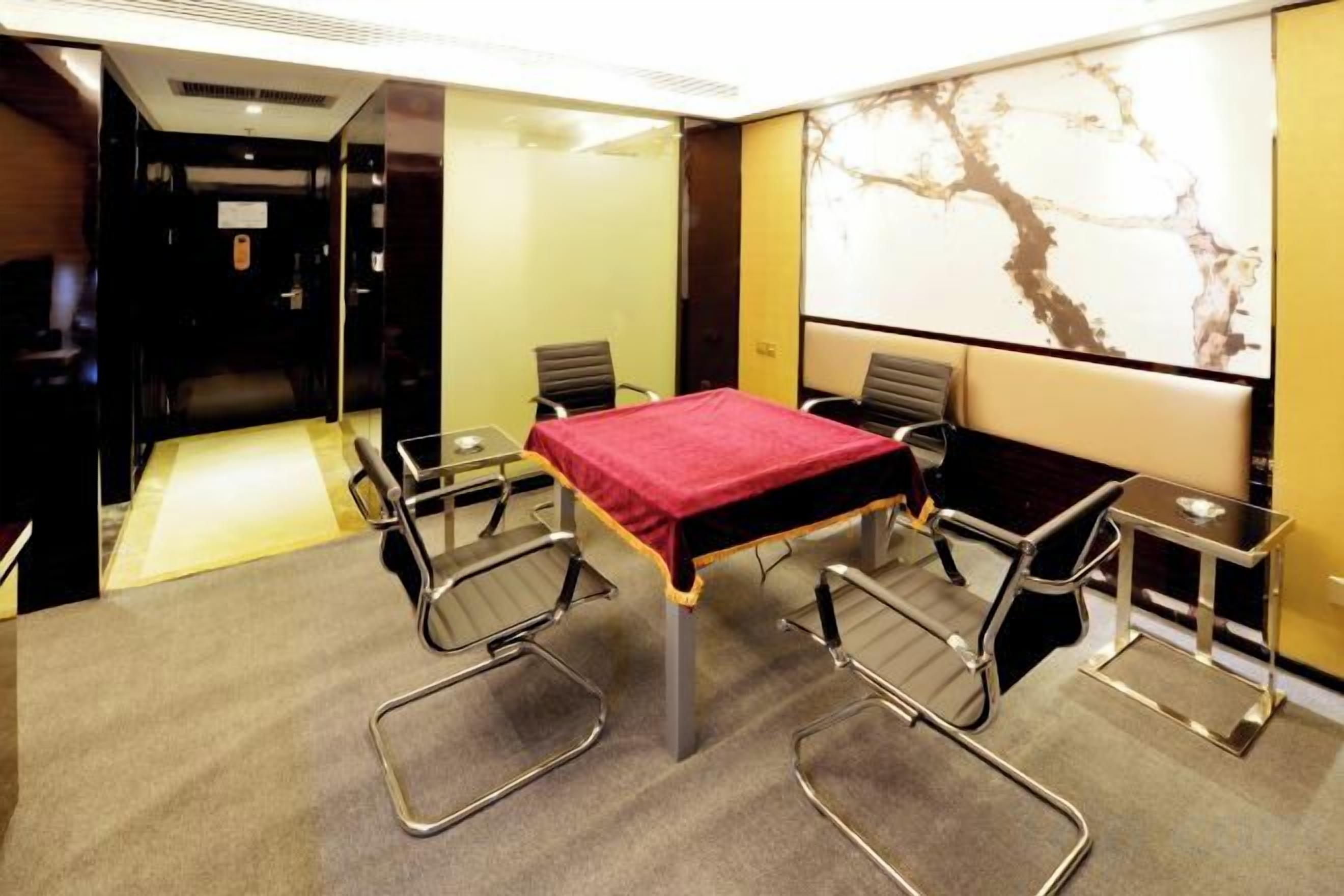 A conference room with a glass table, four chairs, a projector screen, and a large window.