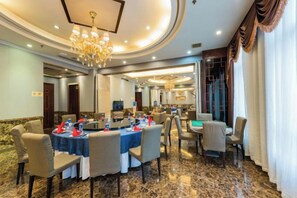 A hotel dining area with round tables, chairs, and a chandelier. - Shenhang International Hotel (Zunyi)