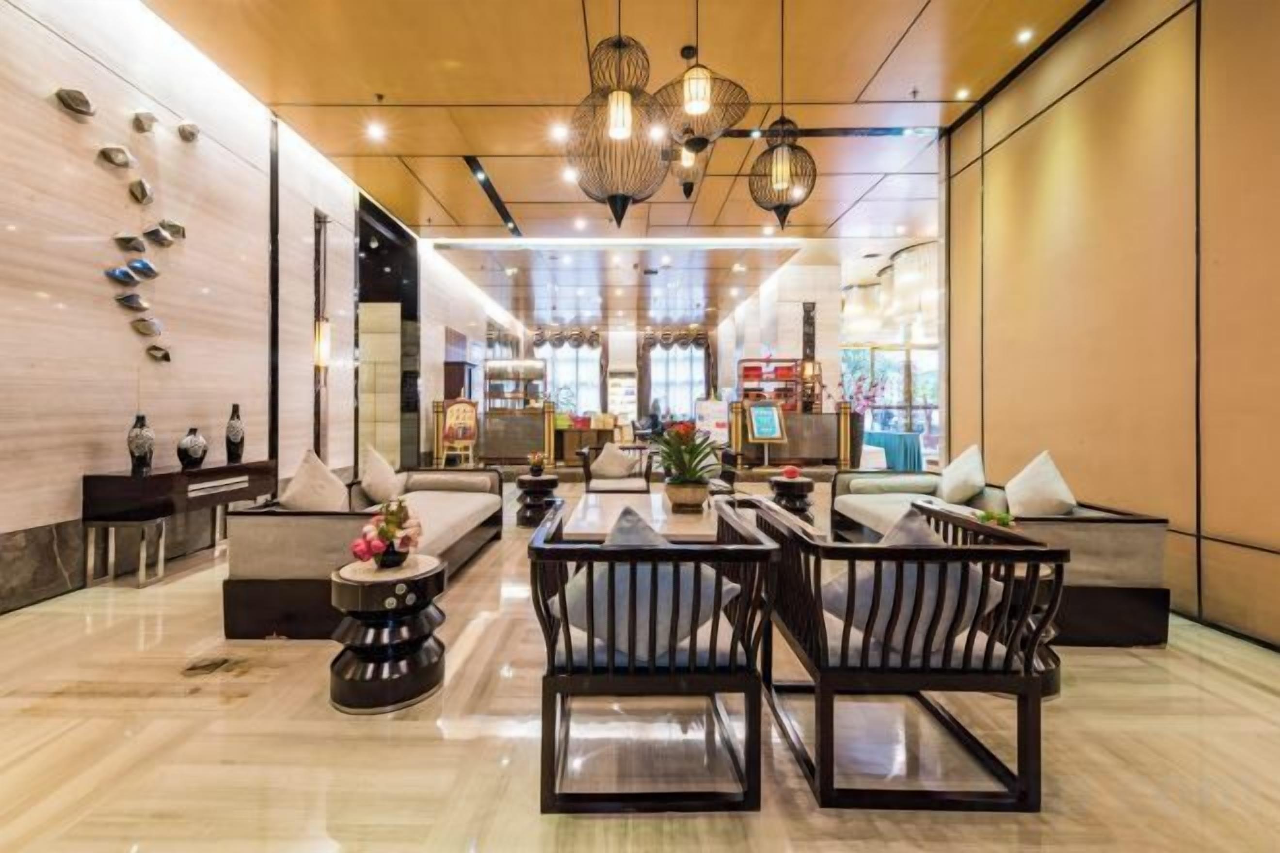 Un hall d’hôtel moderne avec un espace salon, un comptoir d’accueil et une grande fenêtre.