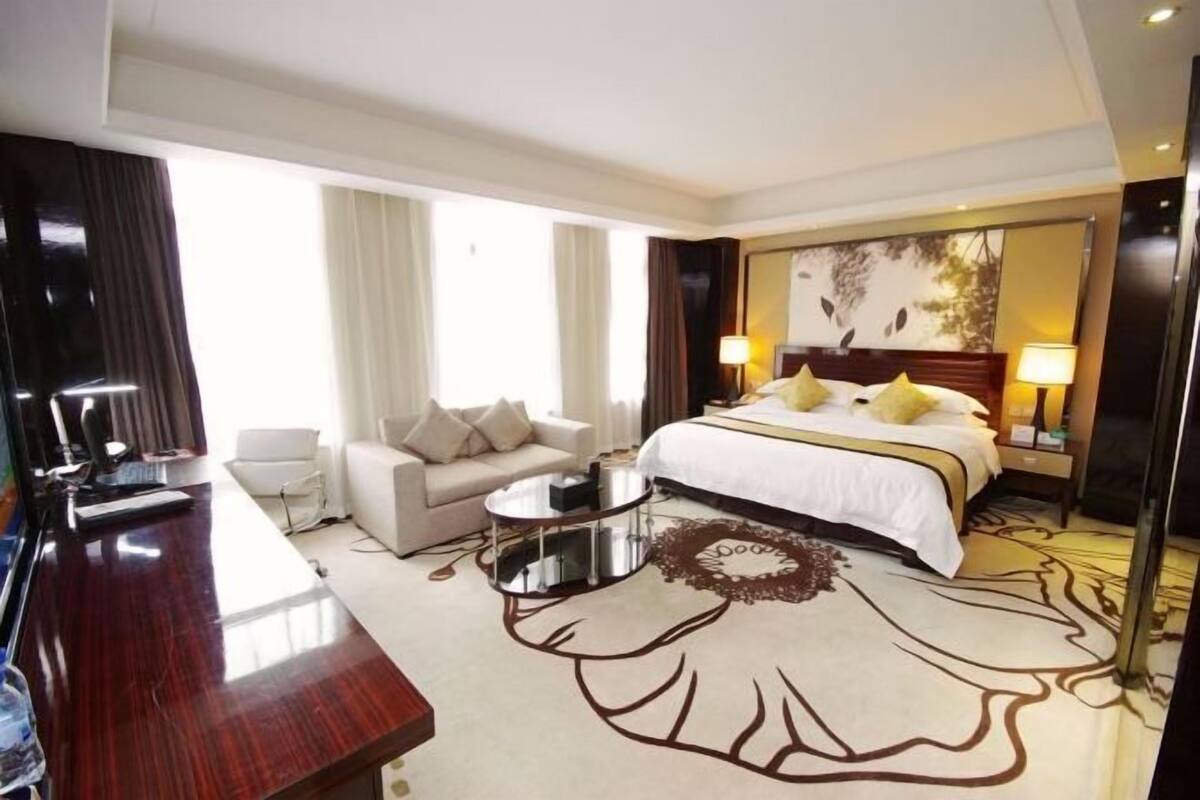 A hotel room with a bed, a sofa, a desk, and a round coffee table.