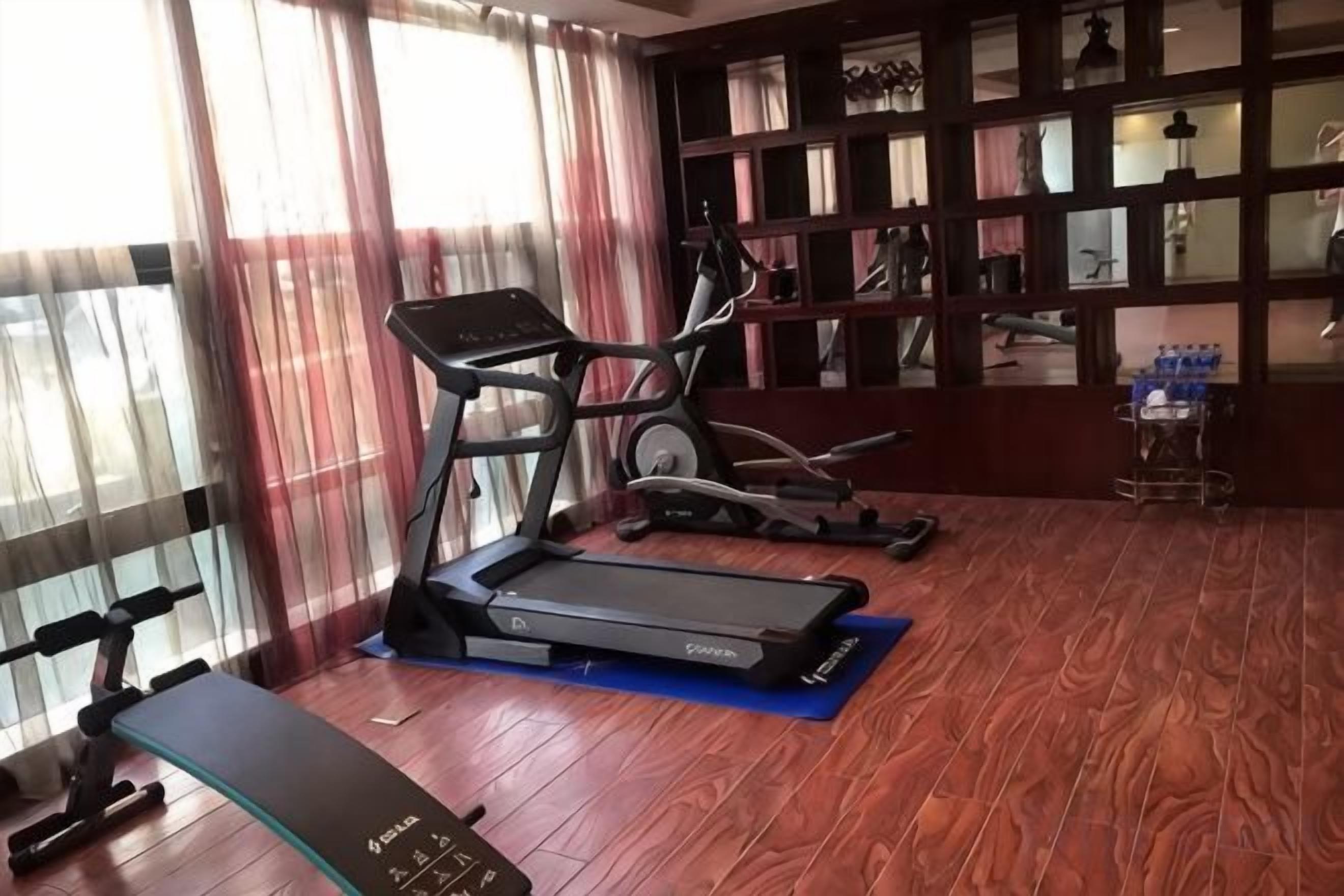 A gym with treadmills, a stationary bike, and a bench.