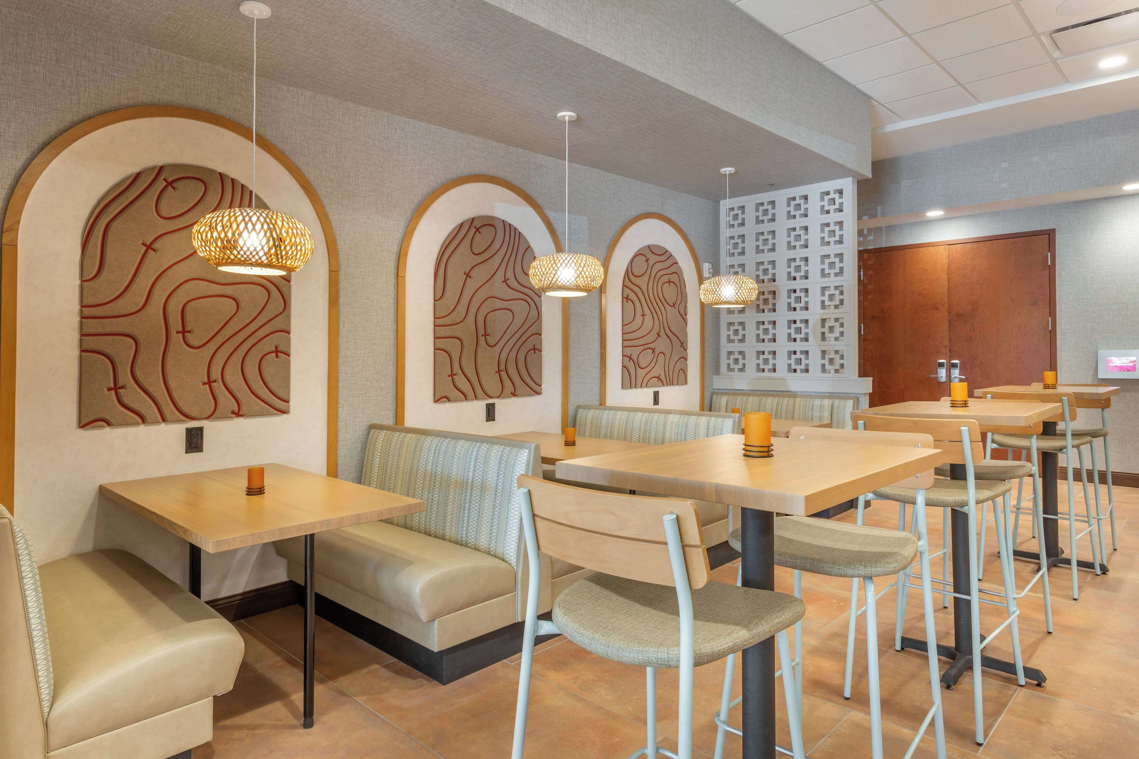 Un restaurante con mesas y cabinas, con arte único en las paredes e iluminación colgante.