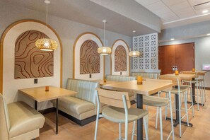 A restaurant with booths and tables, featuring unique wall art and pendant lighting.