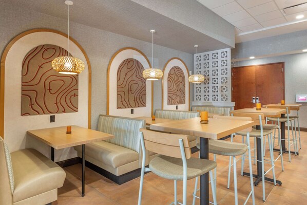 Un restaurante con mesas y cabinas, con arte único en las paredes e iluminación colgante.