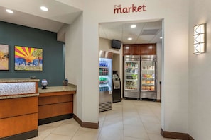 En hotellobby med en receptionsdisk, ett kylskåp och försäljningsautomater.