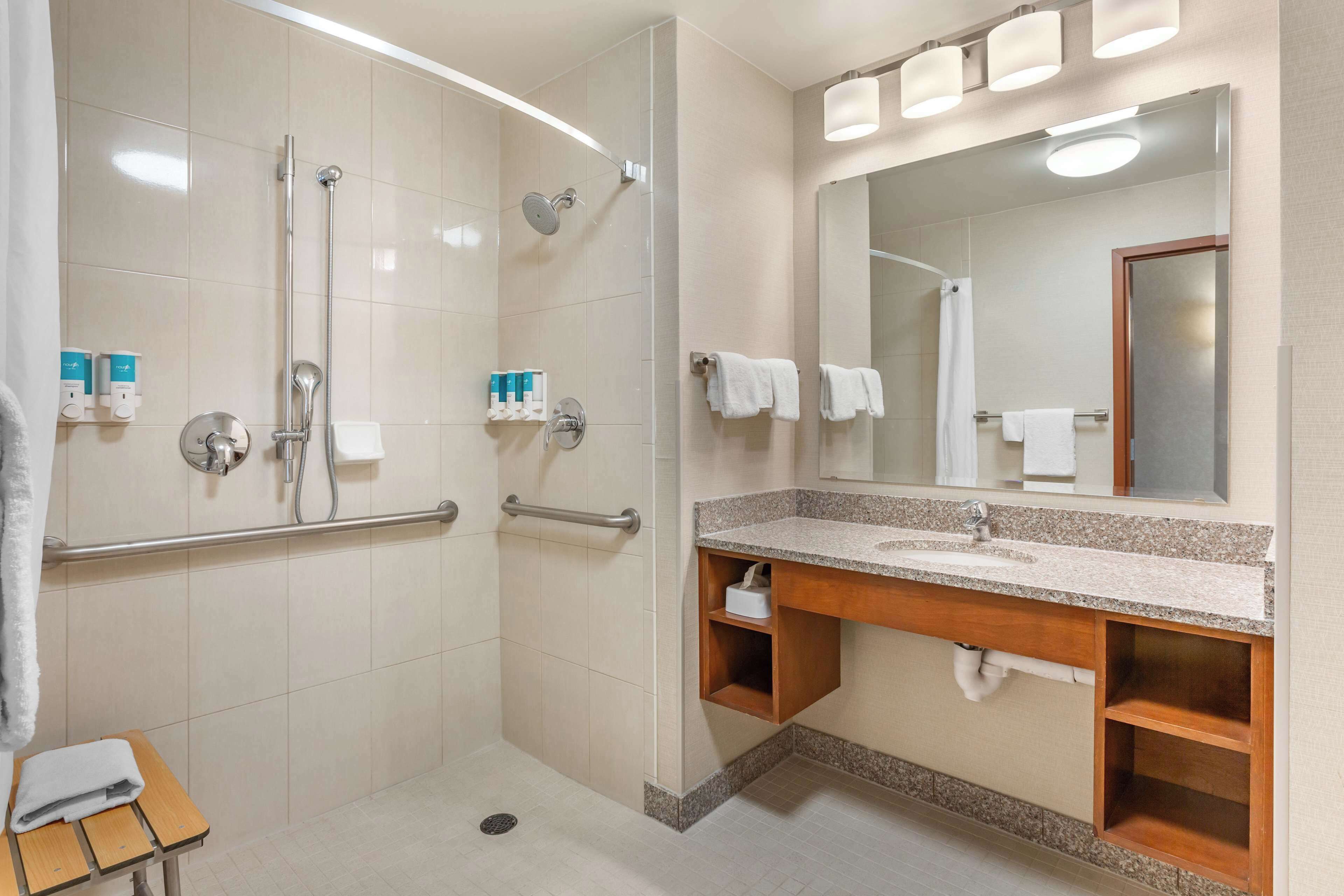Une salle de bain moderne avec une douche à l’italienne, un meuble-lavabo et un grand miroir.