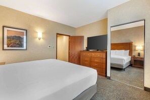 Ett hotellrum med en stor säng, en byrå i trä, en platt-TV och en spegel som reflekterar rummet.