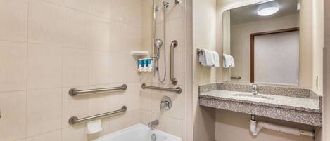 A bathroom with a bathtub, grab bars, a sink, and a mirror.
