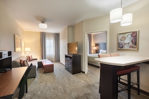 Habitación de hotel con cama, escritorio, televisión, zona de comedor y baño.